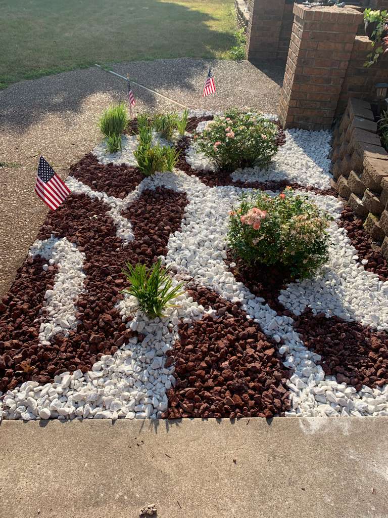 Decorative rock garden with red and white stones and American flags